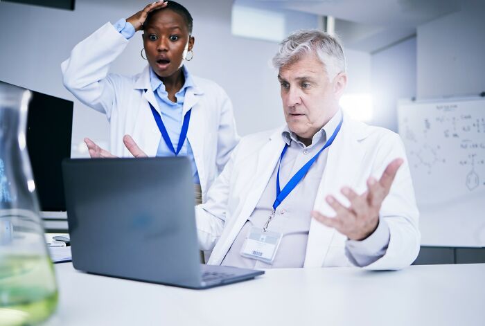 Two doctors looking surprised at a laptop screen while reviewing cases of patients who defied medical odds.