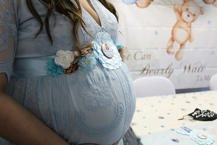 Pregnant woman wearing a blue dress at a baby shower, highlighting strong opinions on grandmas having a baby shower. Pregnant woman wearing a blue dress at a baby shower, highlighting strong opinions on grandmas having a baby shower.