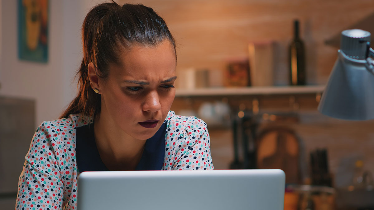 Woman with worried expression looking at laptop, representing family dirty laundry aired out online by stalker half-sister.