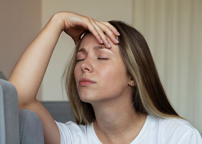 Woman looking stressed and frustrated indoors, reflecting on canceling friend’s holiday booking after harassment issue. Woman looking stressed and frustrated indoors, reflecting on canceling friend’s holiday booking after harassment issue.