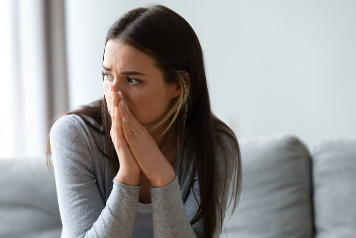 Young woman looking worried and anxious, covering mouth with hands, expressing feelings people would never admit in real life.