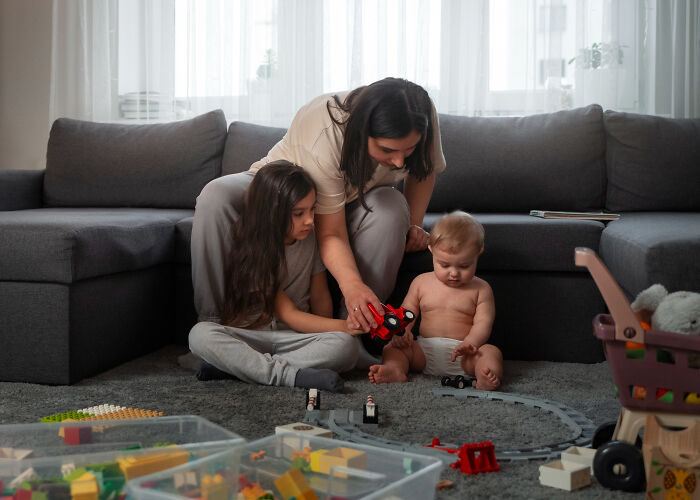 Woman and children playing on floor in living room illustrating signs of a possible spouse causing regret in relationships.