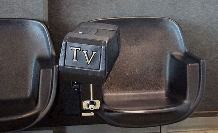 Old-fashioned TV viewing seats with vintage coin-operated television controls, evoking nostalgic memories of past decades.