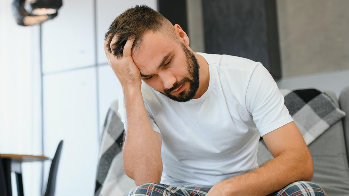 Man sitting indoors looking anxious and stressed during wife's IVF treatment, reflecting husband anxiety after marriage.