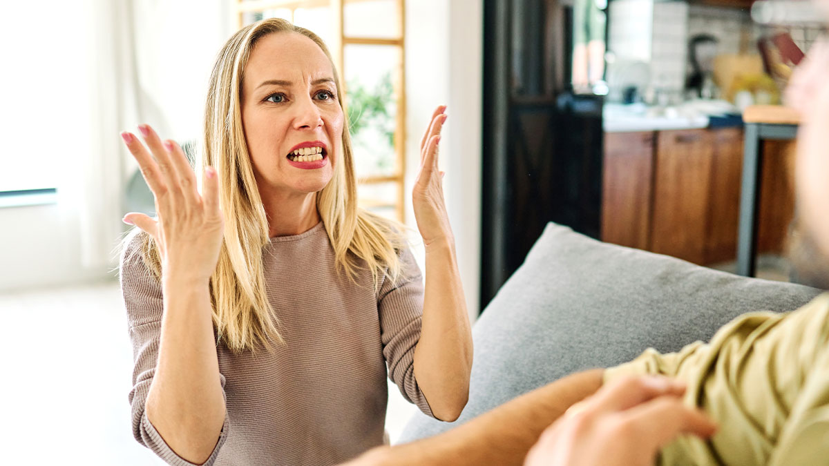 Angry woman arguing with man while sitting on couch, illustrating man refusing to get out of car to check menu.