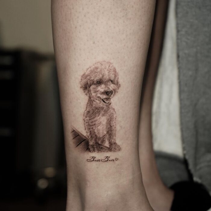 Realistic emotional pet tattoo of a small dog on a person's leg by a Korean tattoo artist.