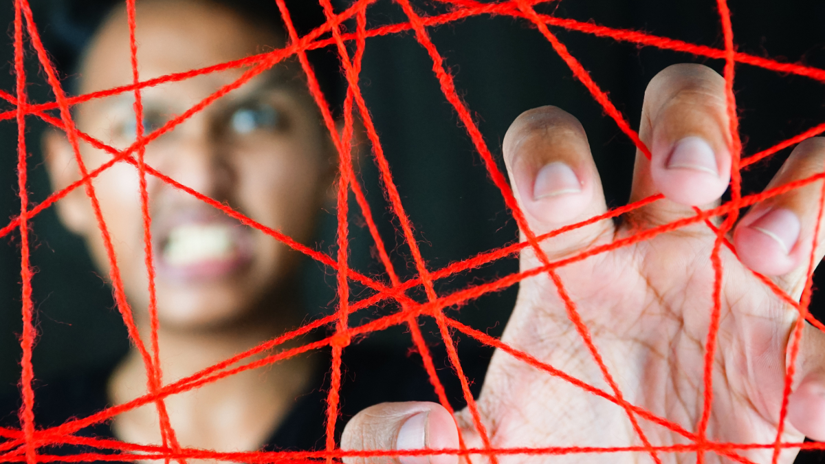 Person reaching through tangled red strings, symbolizing invisible string theory in modern romance and destiny connections.