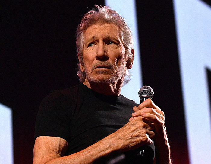Roger Waters holding a microphone on stage, delivering a passionate speech during a live performance.