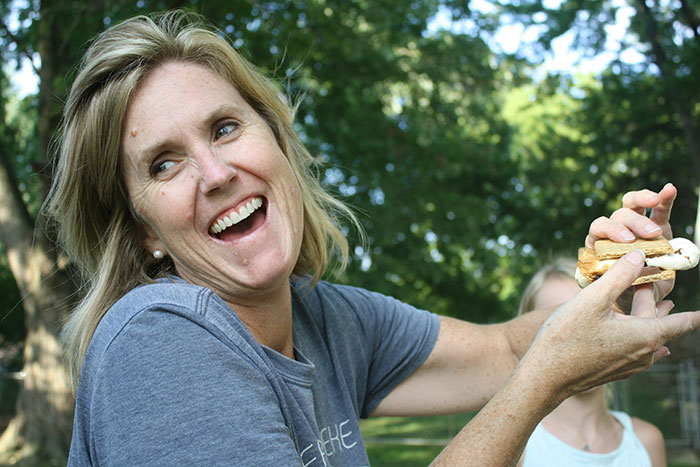 Woman smiling outdoors while holding a s'more, illustrating challenges when inlaws push boundaries during divorce situations.