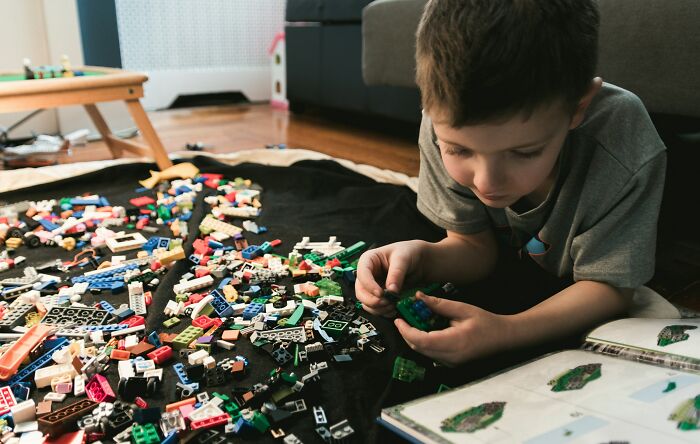 Young boy playing with colorful building blocks on floor using parenting hacks to save sanity at home.