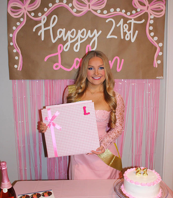 Young woman in a pink dress celebrating a birthday, holding a gift box with pink ribbons and decorations. Young woman in a pink dress celebrating a birthday, holding a gift box with pink ribbons and decorations.