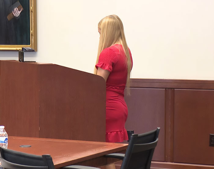 Young woman in red dress standing in courtroom during hearing related to autopsy findings of newborn case Young woman in red dress standing in courtroom during hearing related to autopsy findings of newborn case