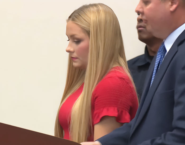 Young woman in red dress at a legal proceeding, related to Kentucky cheerleader case and safe haven baby box details. Young woman in red dress at a legal proceeding, related to Kentucky cheerleader case and safe haven baby box details.