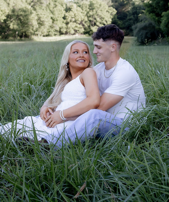 Young couple sitting in tall grass, focusing on the cheerleader arrested for hiding her newborn in a trash bag. Young couple sitting in tall grass, focusing on the cheerleader arrested for hiding her newborn in a trash bag.