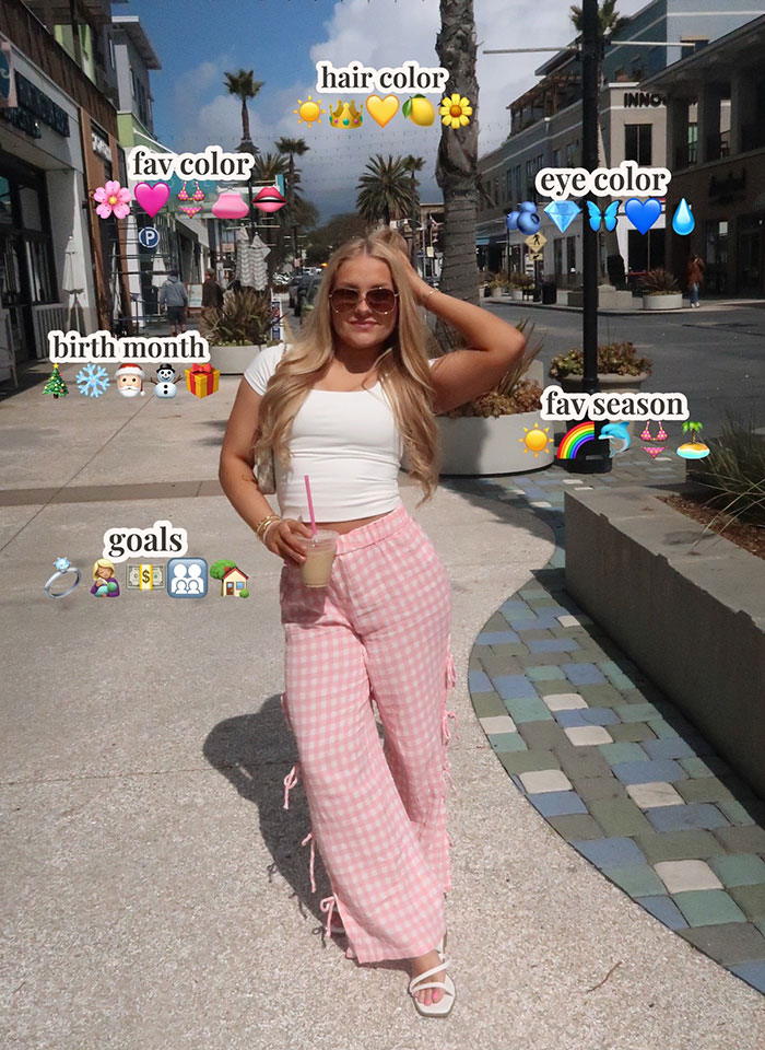 Cheerleader wearing sunglasses and pink pants standing outdoors holding a drink on a sunny day. Cheerleader wearing sunglasses and pink pants standing outdoors holding a drink on a sunny day.