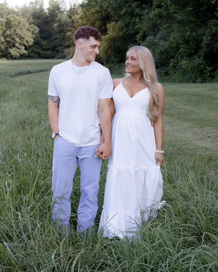 Young couple holding hands outdoors in a grassy field with trees in the background on a sunny day Young couple holding hands outdoors in a grassy field with trees in the background on a sunny day