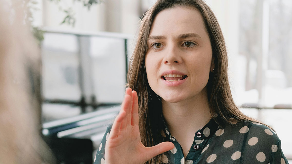 Woman with long brown hair speaking passionately, illustrating the concept of keeping daughters in line during family discussions.