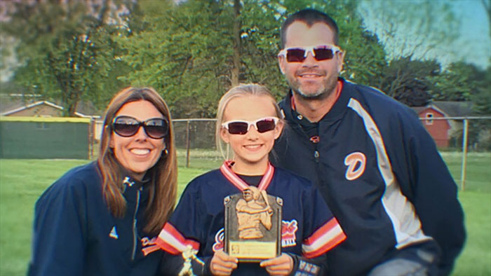 Family at a baseball field with daughter holding a trophy, highlighting a broken person and bullying impact theme. Family at a baseball field with daughter holding a trophy, highlighting a broken person and bullying impact theme.