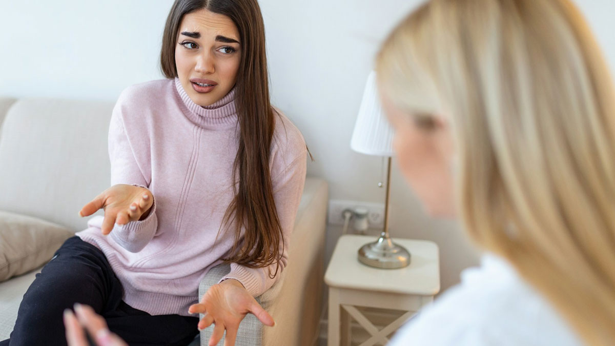 Young woman in pink sweater appearing upset while talking to another person, relating to live-in nanny curfew conflict.