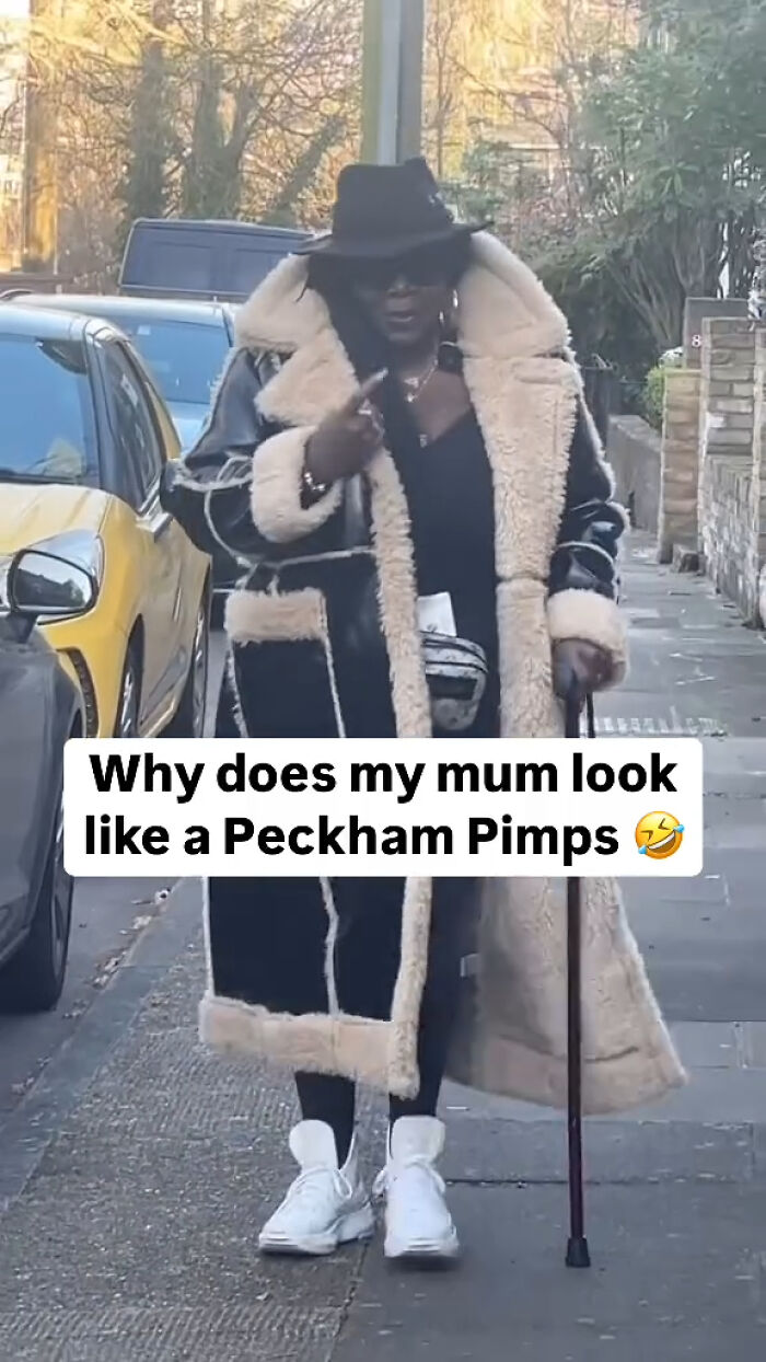 Woman in a shearling coat and hat walking with a cane on a London street, embodying British humor in memes.