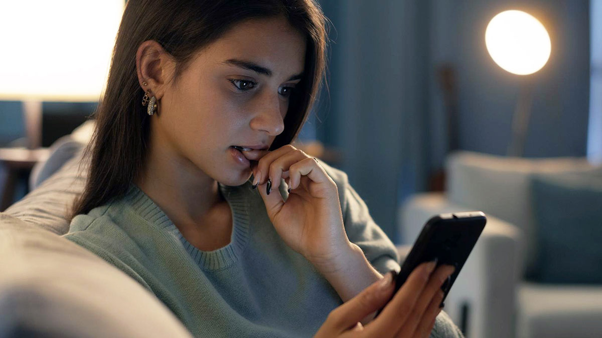 Young woman looking worried while checking her smartphone, concerned about online date's behavior and posts memory.