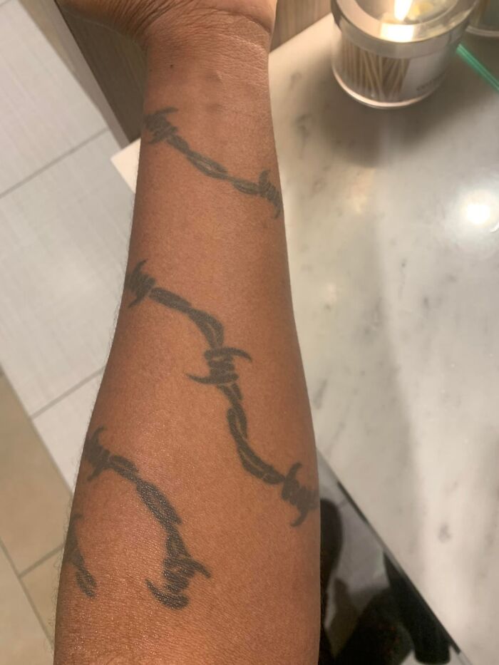 Tattoo of a barbed wire design on a person's forearm, illustrating unusual client tattoo requests.