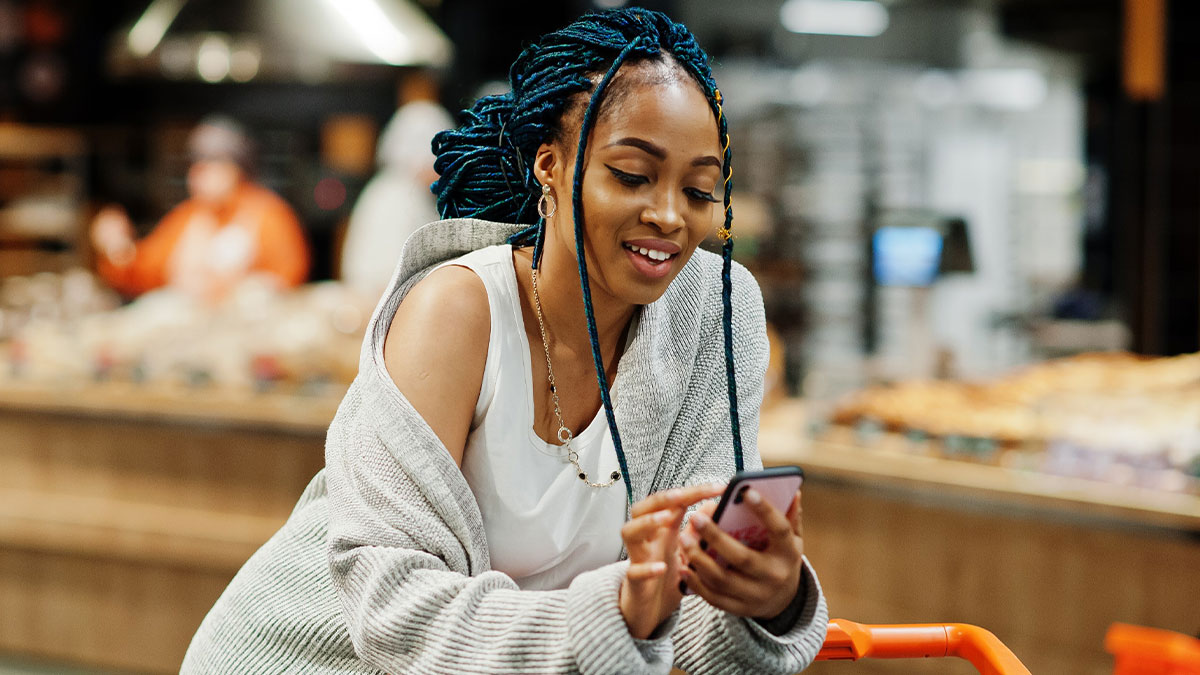 Woman with blue braids using phone in store, representing Americans finding and using a loophole with interest.
