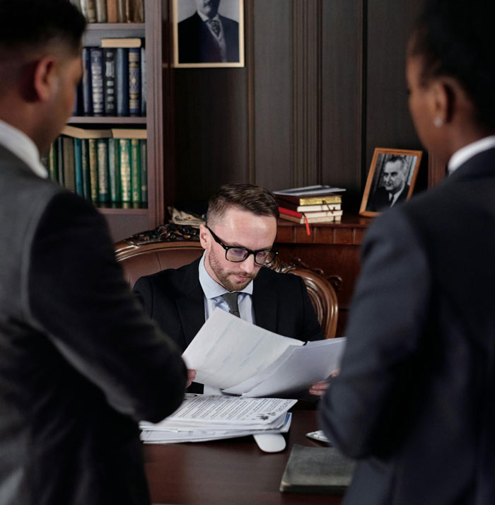 Man in a suit reviewing legal documents in an office, illustrating a man proven not guilty but facing consequences. Man in a suit reviewing legal documents in an office, illustrating a man proven not guilty but facing consequences.
