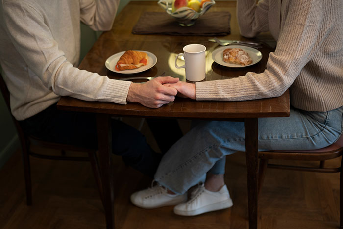 Couple holding hands across breakfast table, illustrating choosing brains over heart in relationships. Couple holding hands across breakfast table, illustrating choosing brains over heart in relationships.