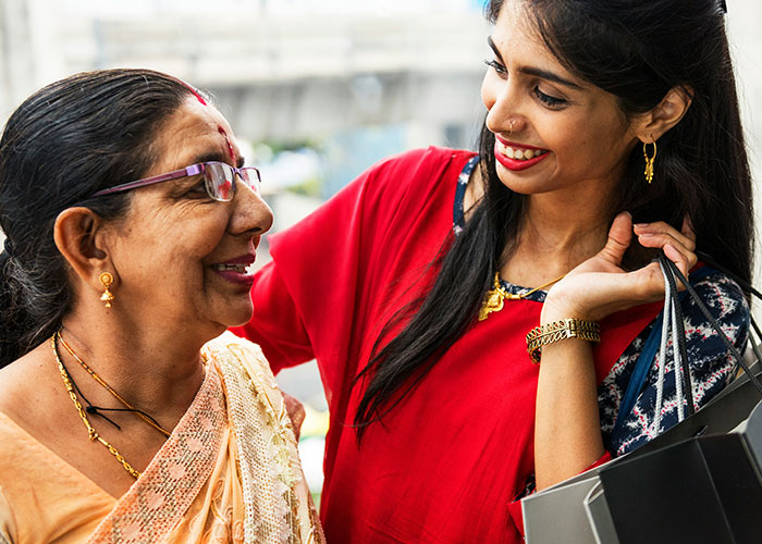 Woman smiling at another woman in traditional attire, hinting at a wedding scene with sister-in-law and bride dynamics. Woman smiling at another woman in traditional attire, hinting at a wedding scene with sister-in-law and bride dynamics.
