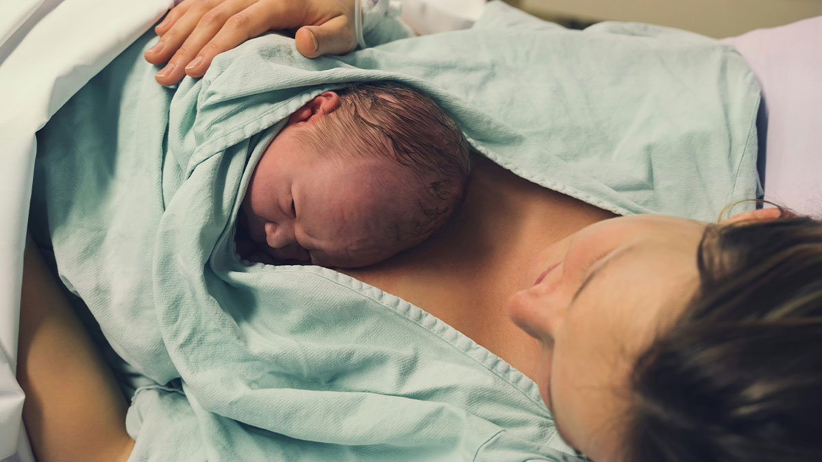 Newborn baby resting on motheru2019s chest wrapped in a blanket, highlighting downplayed medical conditions and procedures.