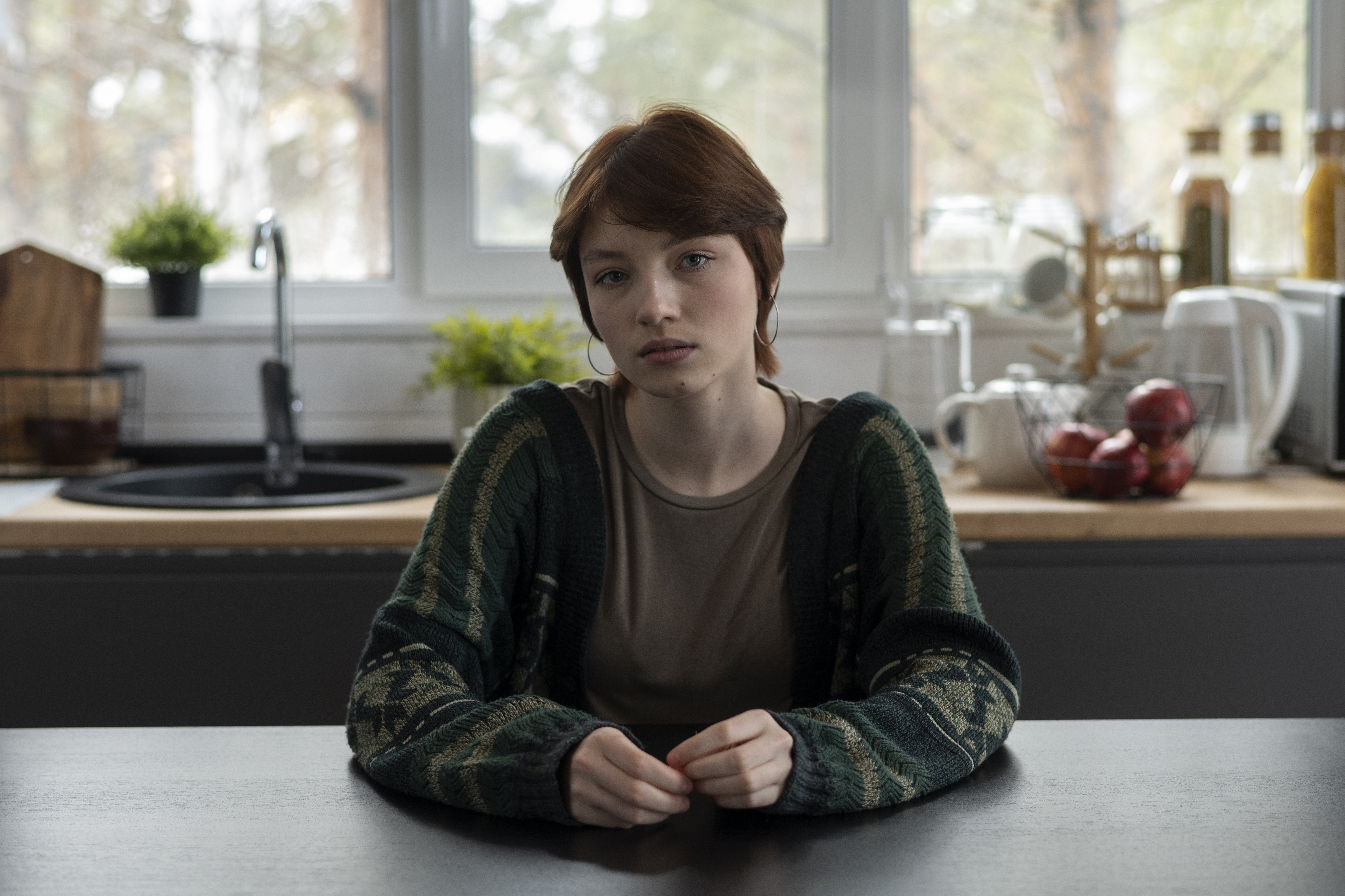 Young woman sitting at kitchen table, looking upset as family demands she gives her baby to her sister. Young woman sitting at kitchen table, looking upset as family demands she gives her baby to her sister.