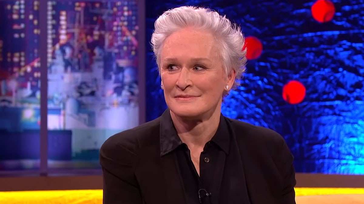 Glenn Close sitting on a talk show set with colorful background, relating to heartwarming celebrity encounters.