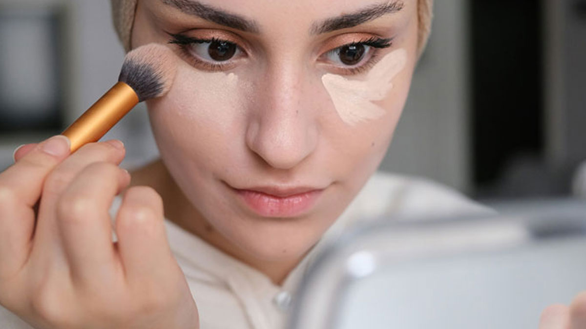 Woman applying makeup with brush, illustrating unexpected things men didnu2019t know about women before dating them