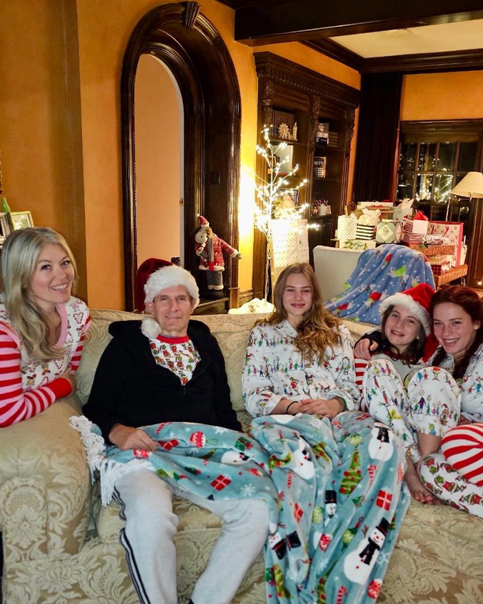 Michael Bolton wearing a Santa hat with family in festive pajamas, seated on a couch during a Christmas celebration. Michael Bolton wearing a Santa hat with family in festive pajamas, seated on a couch during a Christmas celebration.