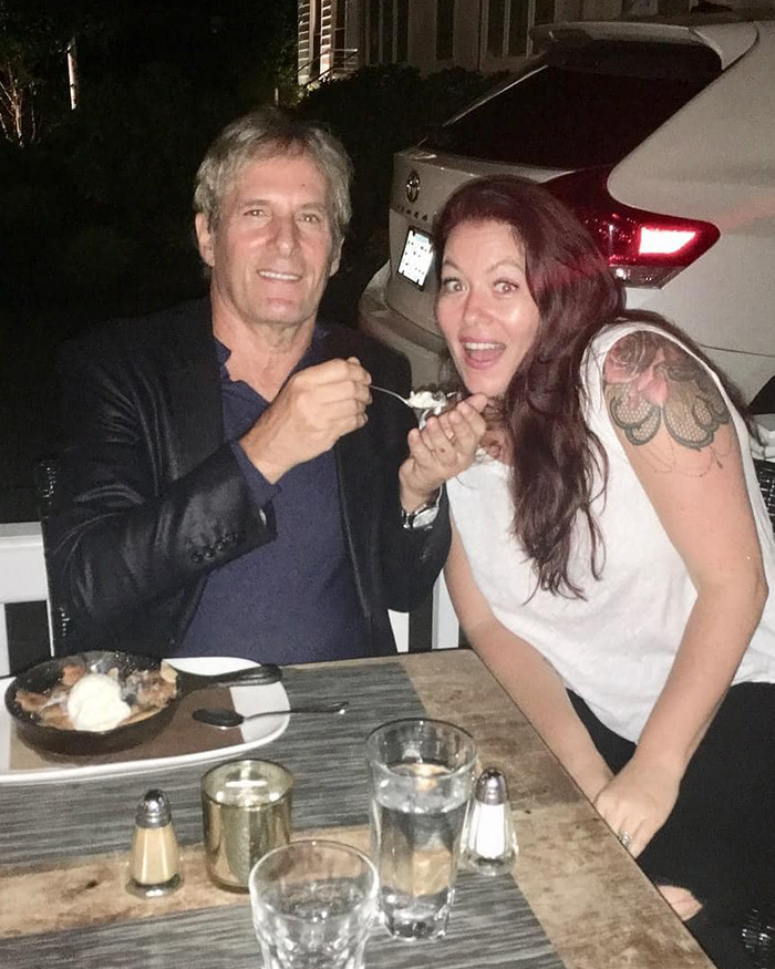 Michael Bolton smiling with a woman at a table, sharing a dessert, highlighting symptom before heartbreaking diagnosis. Michael Bolton smiling with a woman at a table, sharing a dessert, highlighting symptom before heartbreaking diagnosis.