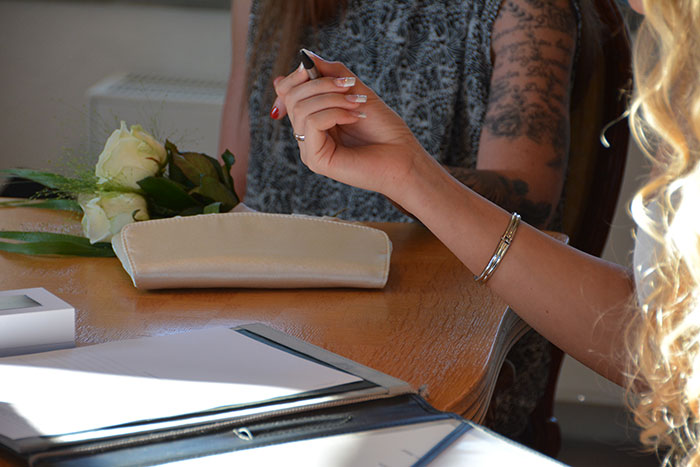 Two women discussing HOA rules at a wooden table with documents and white roses, highlighting HOA house disputes.