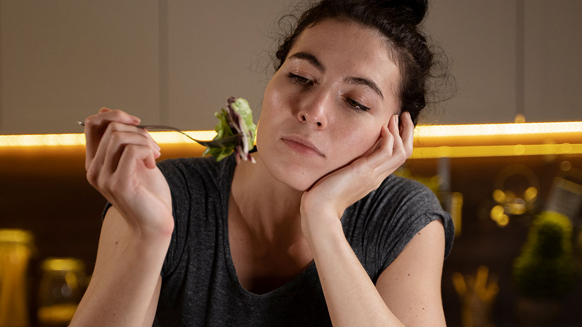 Woman looking annoyed while holding a fork with salad, illustrating a story about allergies and family conflict.