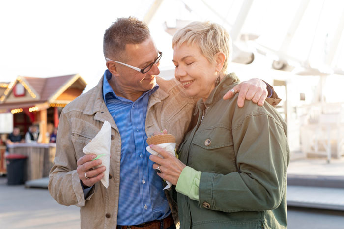 Couple enjoying ice cream together outdoors, highlighting family bonding challenges and emotional distance with son. Couple enjoying ice cream together outdoors, highlighting family bonding challenges and emotional distance with son.