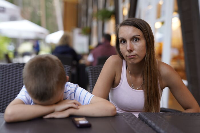 Worried mother sitting at a table with her out of control 4-year-old son after joining nursery, seeking advice. Worried mother sitting at a table with her out of control 4-year-old son after joining nursery, seeking advice.