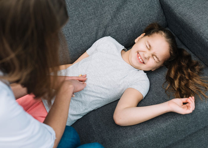 Young woman caring for a disabled daughter lying on a couch while mother tries to involve her 20-year-old son. Young woman caring for a disabled daughter lying on a couch while mother tries to involve her 20-year-old son.