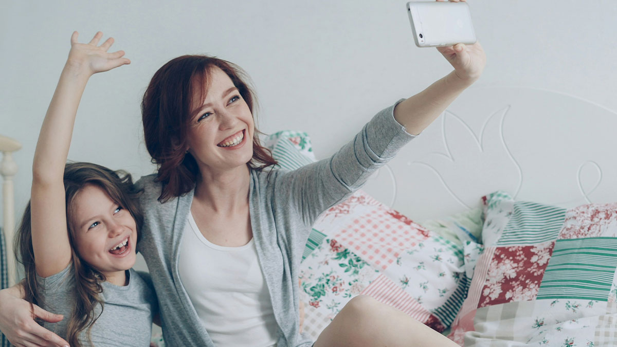 A joyful mom and daughter taking a selfie together, illustrating TikTok moms capturing moments with a smartphone.