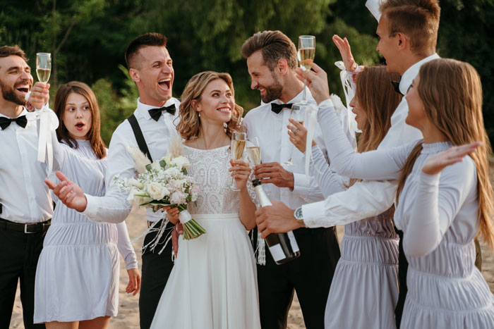 Bride and bridal party celebrating outdoors, dressed in white, raising champagne glasses at a joyful wedding gathering. Bride and bridal party celebrating outdoors, dressed in white, raising champagne glasses at a joyful wedding gathering.