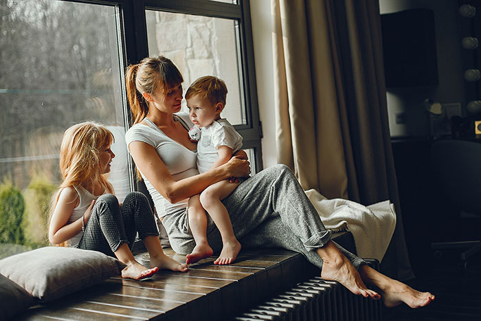 Woman sitting with two children by the window while her dogs are locked up during a house sit incident. Woman sitting with two children by the window while her dogs are locked up during a house sit incident.