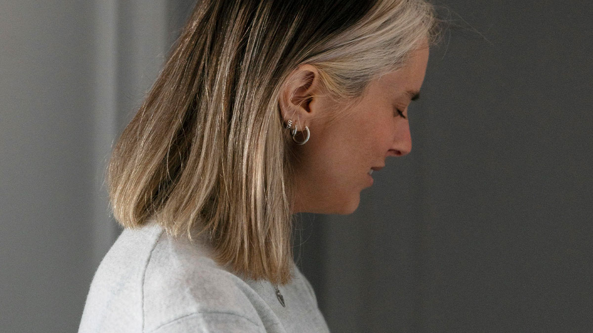 Woman with blonde hair looking down, reflecting on a woman catching her mom sleeping with her husband affair.