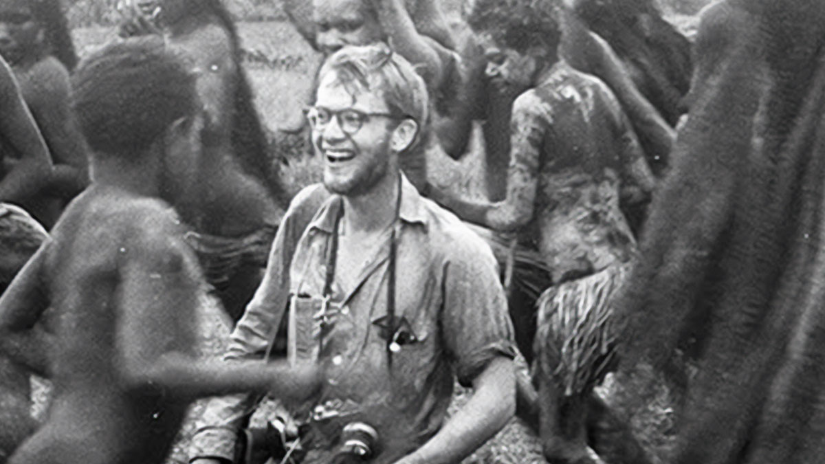 Young man with camera smiling among children covered in mud, a photo that seems normal until you learn the mysteries behind it