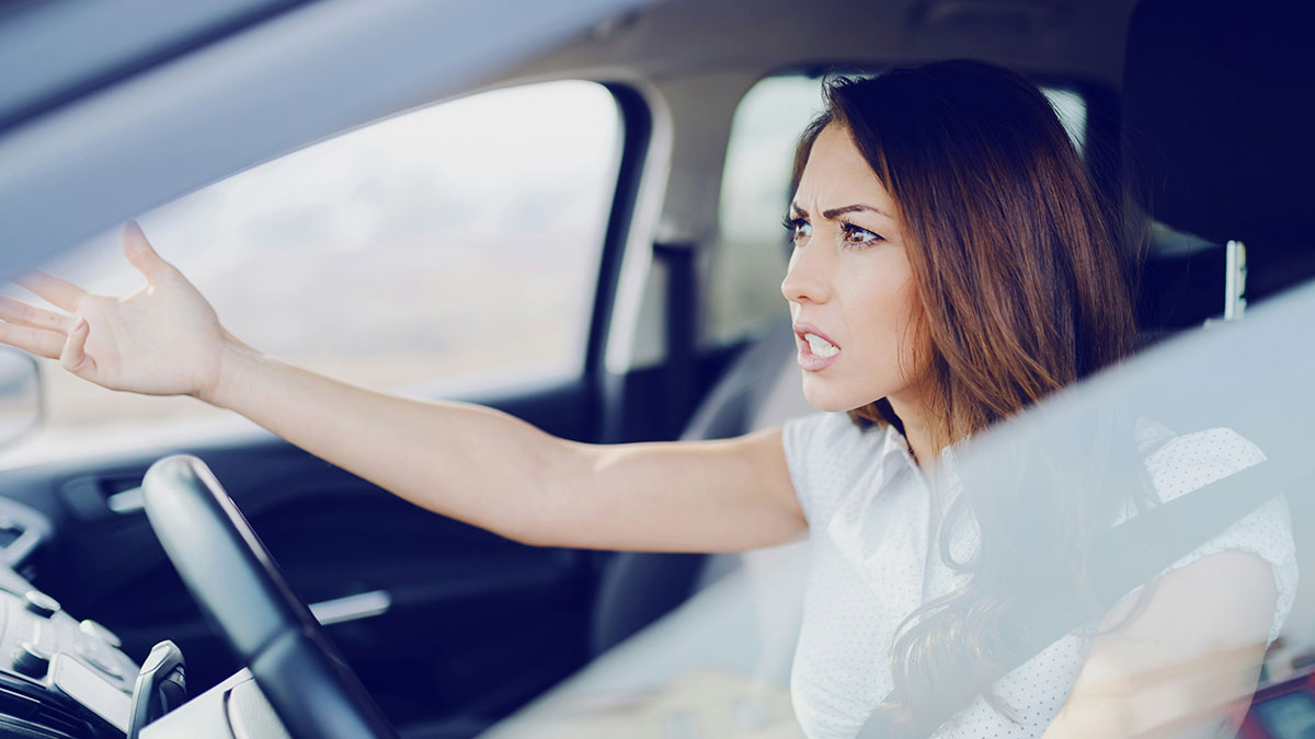 Angry nurse in car after a 12-hour shift, frustrated about neighbor using her driveway again.