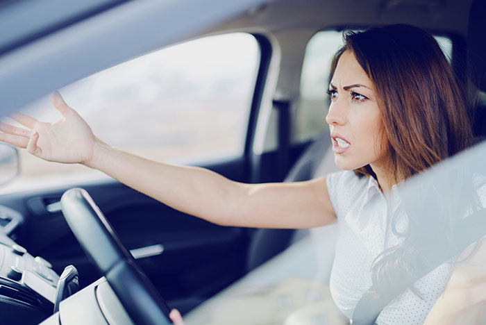 Nurse frustrated inside car after a long shift, reacting angrily to neighbor using her driveway again. Nurse frustrated inside car after a long shift, reacting angrily to neighbor using her driveway again.