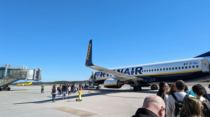 Passengers boarding a Ryanair plane on a clear day amid chaos caused by eating and flushing passports during flight. Passengers boarding a Ryanair plane on a clear day amid chaos caused by eating and flushing passports during flight.