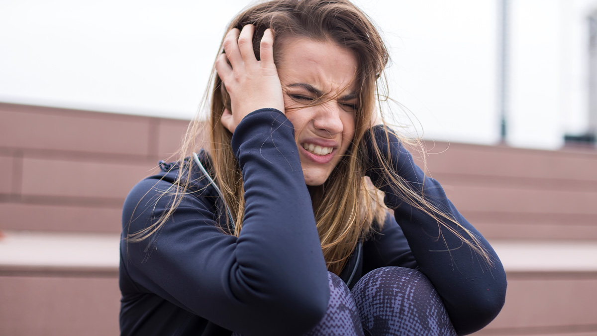 Young woman crying outdoors, distressed while sitting on stairs, relating to woman demands to marry in strangeru2019s backyard scenario.